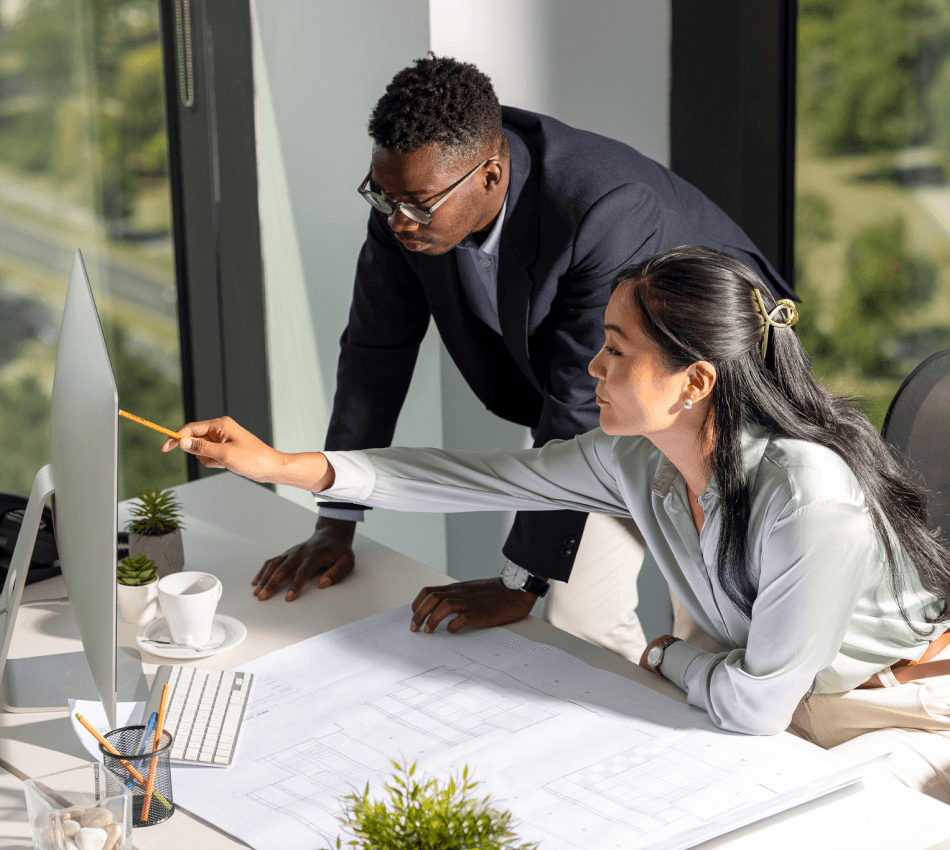 Two architects plan a design on a large monitor.